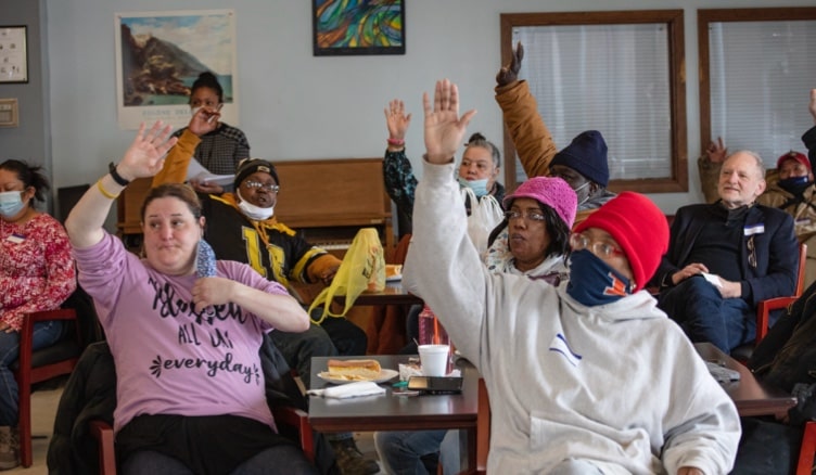 A group of C4's clients raise their hands to answer a question